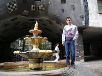 2016.09.17 Вена, дом Хундертвассера (Hundertwasserhaus), его «оплывшая» арка с «заплатками», фонтан с «наплывом» тротуара на бортик.