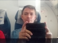 2022-08-17. Experiments of an inexperienced self-portraitist in an airplane display: the horizontal orientation of the smartphone, the glance caught in the lens.