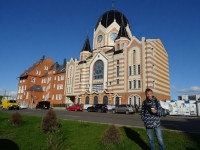 2022-10-09. Against the background of the New Synagogue of Kaliningrad ✡︎, with electrical wires removed from the original photograph by a Chinese AI named Qwen.