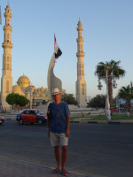 Against the background of the Grand Port Mosque in Hurghada and some kind of monument with the national flag of Egypt.