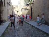 Одна из улиц Старого города Родоса (Παλιά πόλη Ρόδου), мощёная, как и многие, но нетипично наклонённая. Весьма многолюдно.
