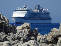 12-палубный круизный лайнер “Celebrity Infinity” (номер IMO: 9189421) с другого бока и красиво на фоне камней-волнорезов бухты Мандракий (μαρίνα Μανδρακίου).