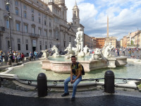 Я сижу на ограде фонтана Мавра (Fontana del Moro) на площади Навона (Piazza Navona).