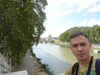 Я на фоне Тибра (Tiberis), текущего по вечному Риму (Roma Aeterna) к собору святого Петра (Basilica Sancti Petri) в Ватикане (вдалеке).