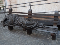 Памятник бездомному… Иисусу (Monumento a Gesù homeless, 2018) на площади святого Эгидия. Если сомневаетесь, что это Иисус – обратите внимание на дырки от гвоздей 😯 на его ногах, которыми он в том числе был прибит к кресту. Оригинал бронзовой статуи придумал канадский скульптор Тимоти Шмальц (Timothy Schmalz), в 2013 году установив его в Торонто (Канада). С тех пор по миру появилось более 50 копий, включая данную.