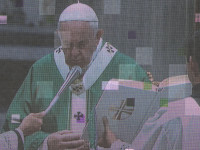 Папа римский Франциск (Franciscus, правил в 2012 – 2025 годах) на большом экране, транслирующим его службу в соборе святого Петра (Basilica Sancti Petri) на одноимённую площадь (Piazza San Pietro).