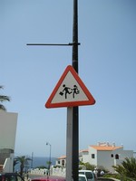 Пуэрто-де-Сантьяго (Puerto de Santiago), проспект 5° столетия (Avenida 5° Centenario). Дорожный знак 1.23 «Дети» на Тенерифе более затейливый, чем в России: бегут мальчик и девочка (с косичкой!), у него – портфель (дипломат?), у неё – сумочка (клатч?). 😊